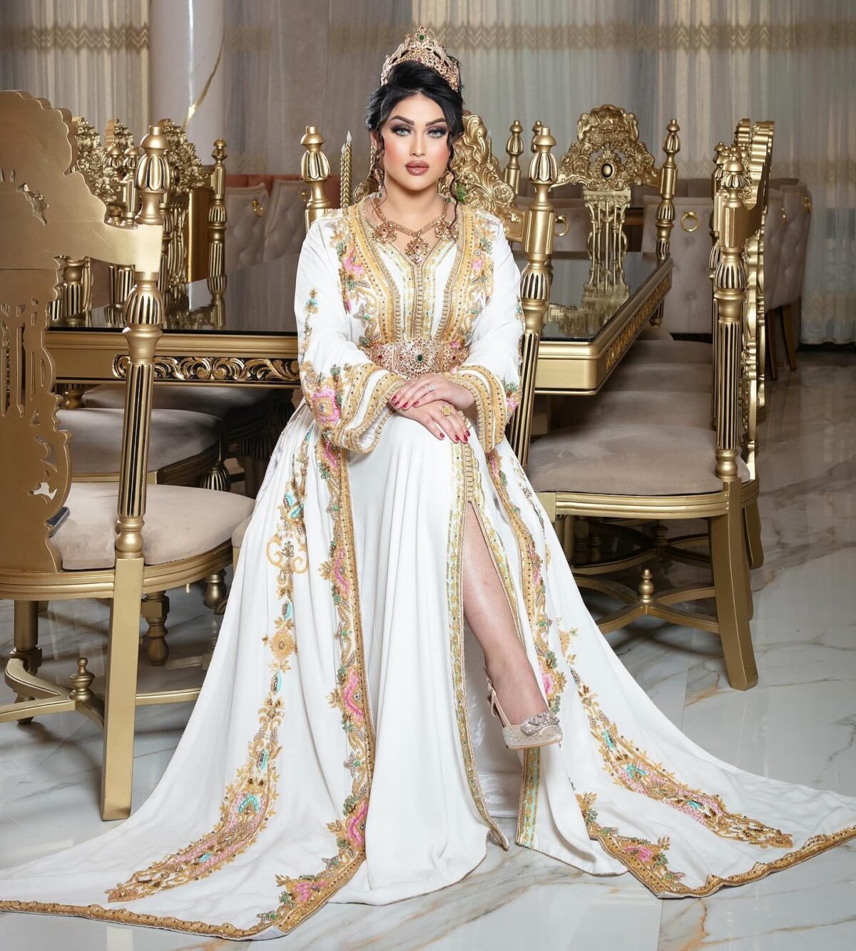Caftan En Ligne Découvrez l'élégance intemporelle du caftan henna, une pièce traditionnelle marocaine magnifiquement ornée. Nos caftans en henna allient beauté et tradition pour des moments inoubliables. Explorez notre collection unique aujourd'hui ! Le Caftan Maroua se compose de deux pièces en crêpe de soie blanc, travaillé en broderies dorées, roses fuchsia et pistache, de sfifa et de boutons en skali bronze, perlés entièrement à la main en cristal. Le bas est confectionné en drap de soie blanc et est accompagné d'une ceinture assortie.
