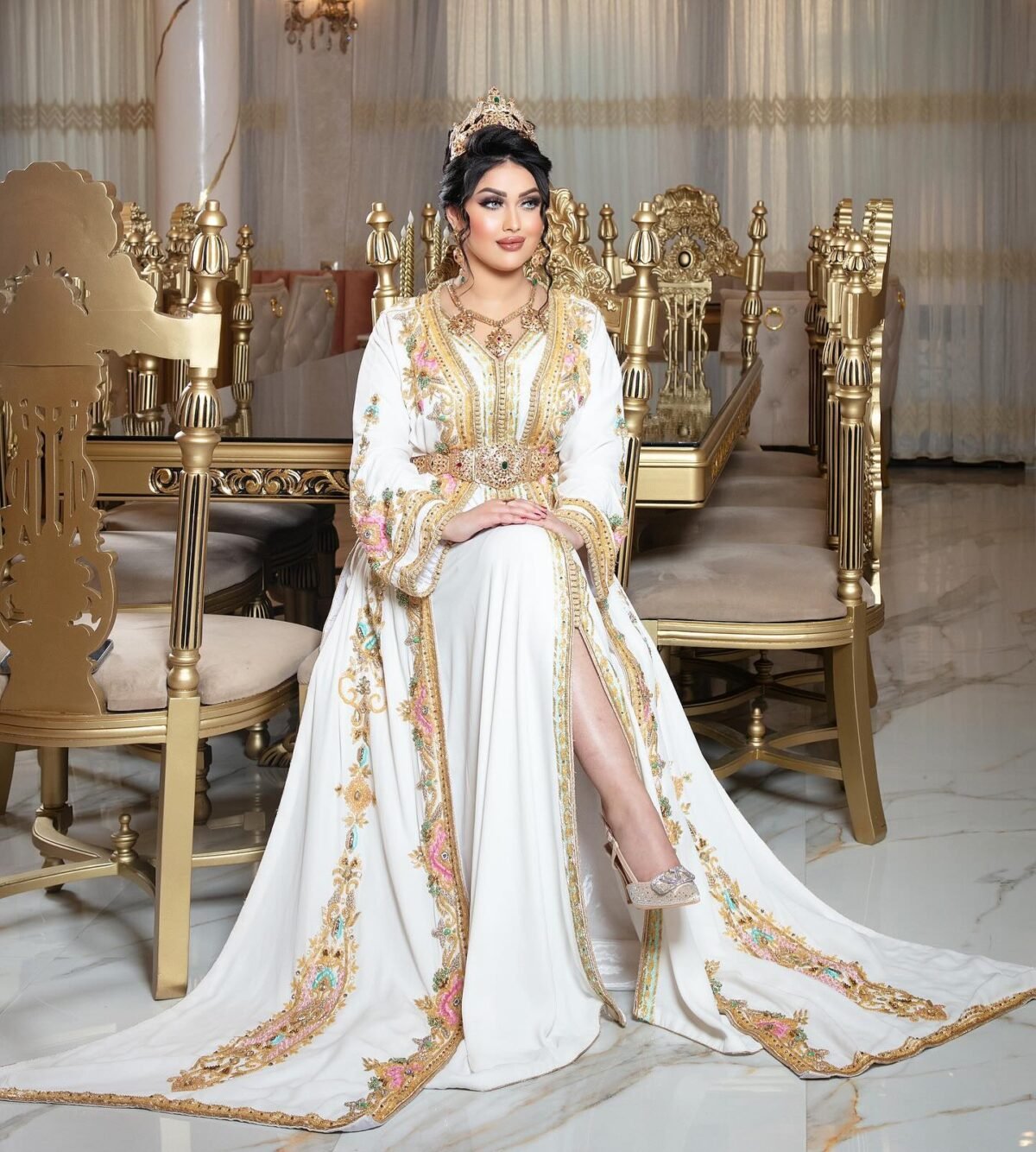 Caftan En Ligne Découvrez l'élégance intemporelle du caftan henna, une pièce traditionnelle marocaine magnifiquement ornée. Nos caftans en henna allient beauté et tradition pour des moments inoubliables. Explorez notre collection unique aujourd'hui ! Le Caftan Maroua se compose de deux pièces en crêpe de soie blanc, travaillé en broderies dorées, roses fuchsia et pistache, de sfifa et de boutons en skali bronze, perlés entièrement à la main en cristal. Le bas est confectionné en drap de soie blanc et est accompagné d'une ceinture assortie.